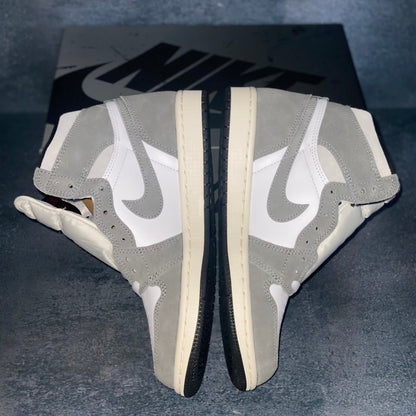 The medial side of the white and grey Nike Air Jordan 1 Retro High sneakers with a black and grey Nike Air Jordan sneaker box.