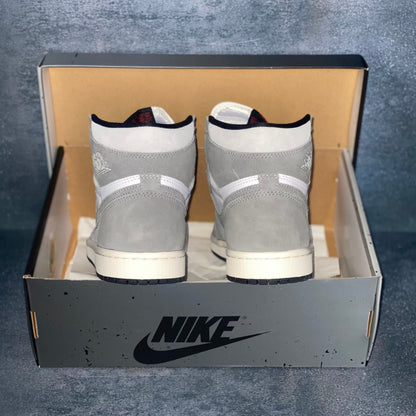 The heels of the white and grey Nike Air Jordan 1 sneakers with a black and grey Nike Air Jordan sneaker box.