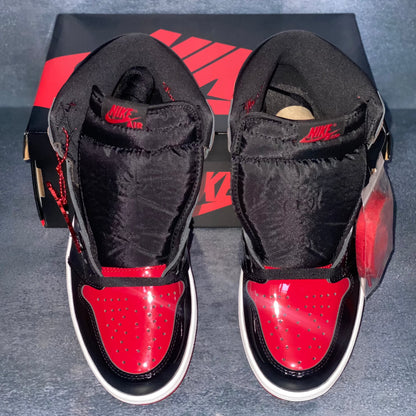 Black and red patent leather Nike Air Jordan 1 Retro High sneakers with a black and red Nike Air Jordan sneaker box.