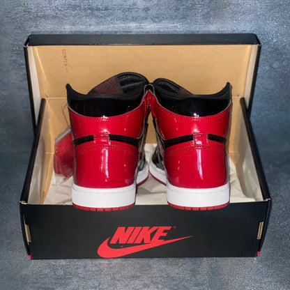 The heels of the black and red patent leather Nike Air Jordan 1 Retro High sneakers with a black and red Nike Air Jordan sneaker box.