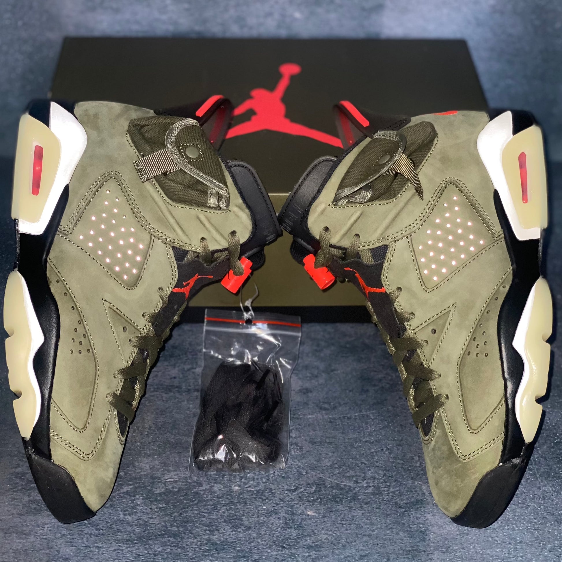 The lateral side of the military green Air Jordan 6 Travis Scott sneakers with a green and black Air Jordan Travis Scott sneaker box.