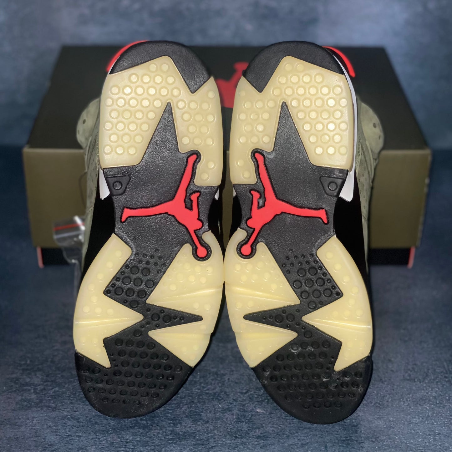 The translucent sneaker bottom also known as ice of the military green Air Jordan 6 Travis Scott sneakers with a green and black Air Jordan Travis Scott sneaker box.