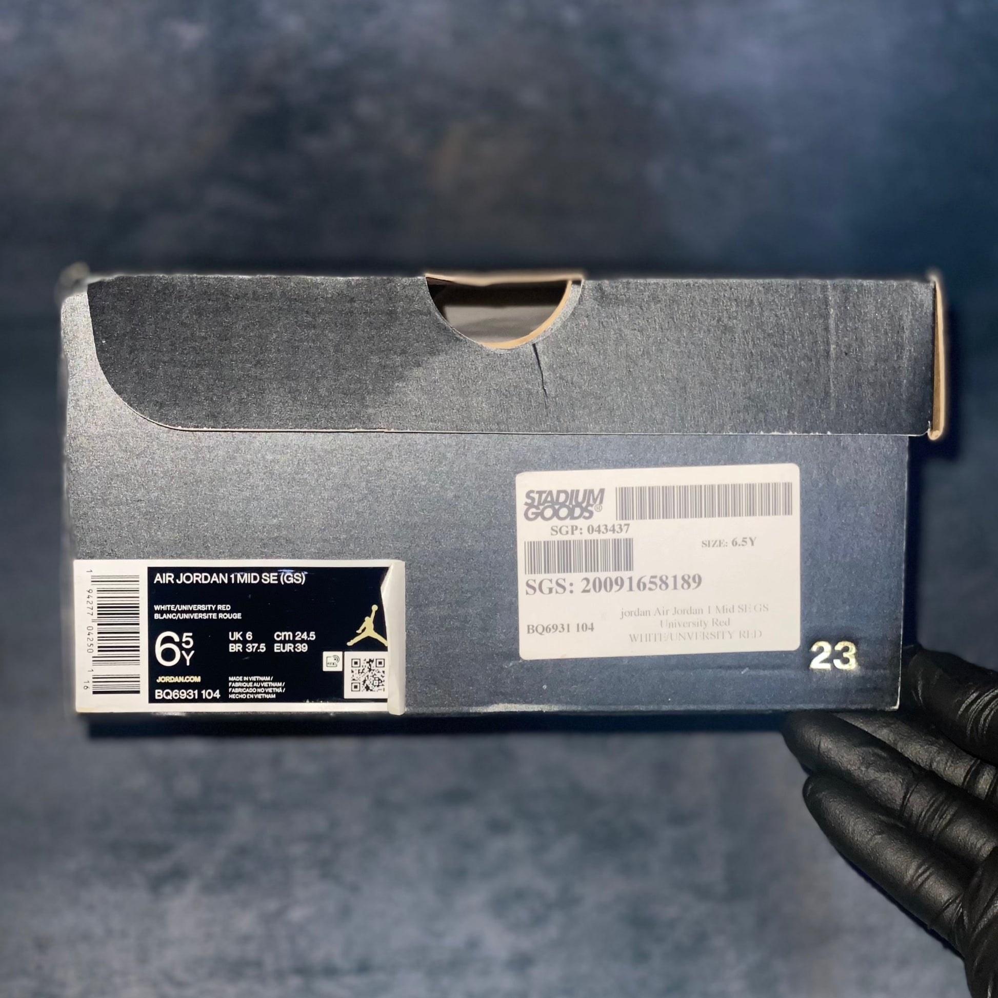 Black Air Jordan 1 Mid sneaker box with the barcode, style code, size, and other sneaker information on a label.