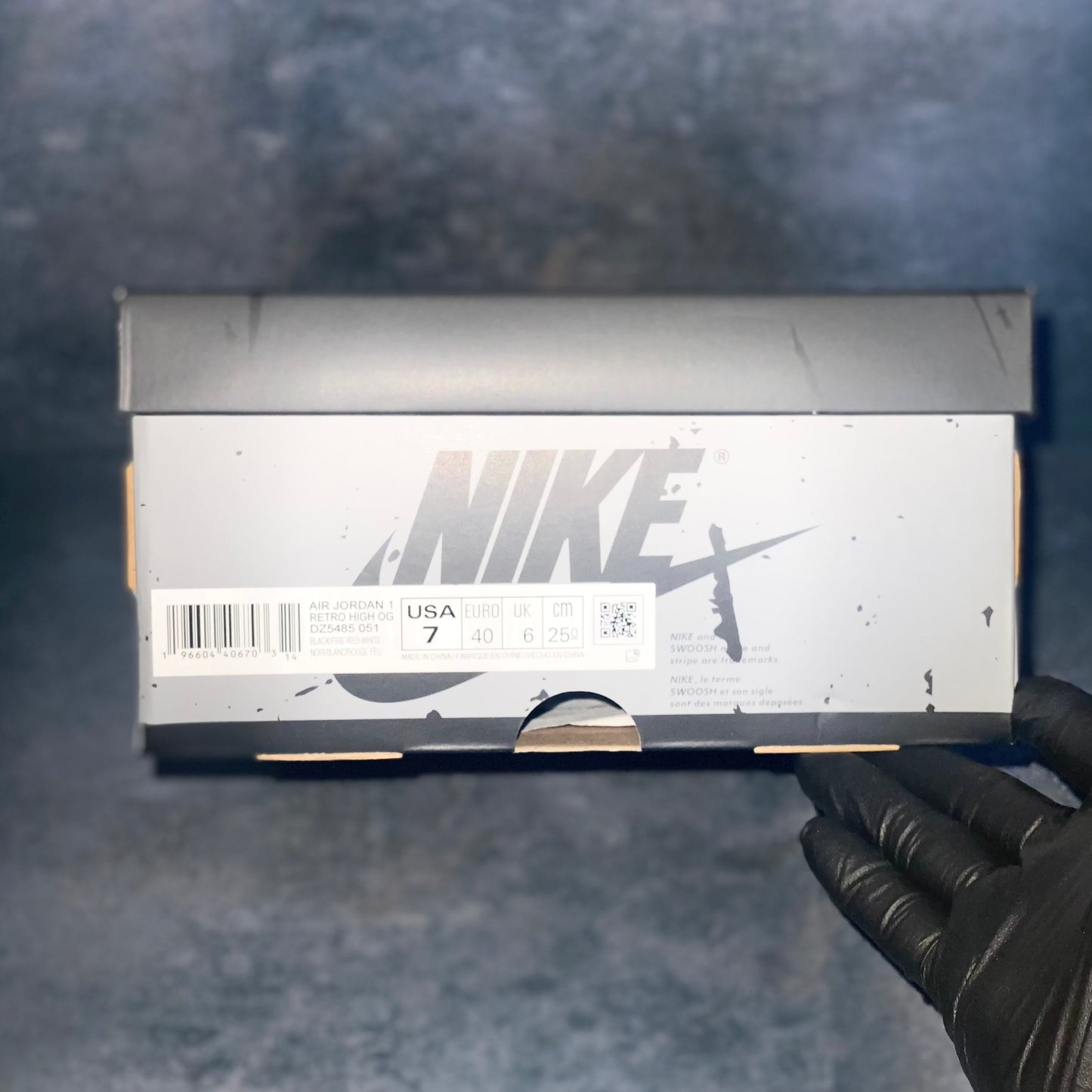 Black and grey Nike Air Jordan 1 Retro High sneaker box with the barcode, style code, size, and other sneaker information on a label.