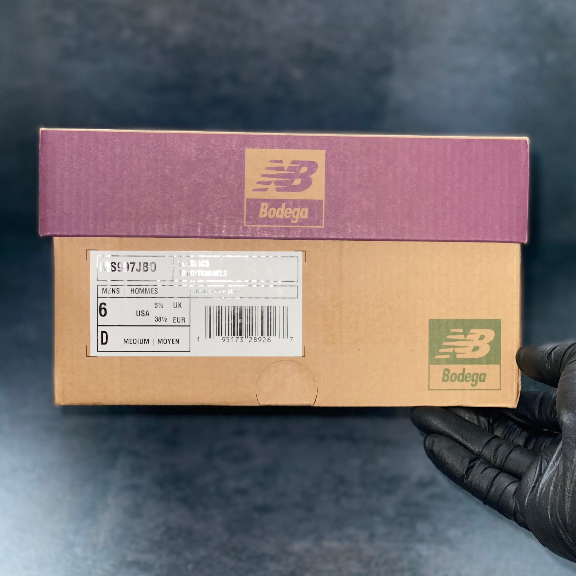 The burgundy and brown New Balance Bodega sneaker box with the barcode, style code, size and other sneaker information on a label.